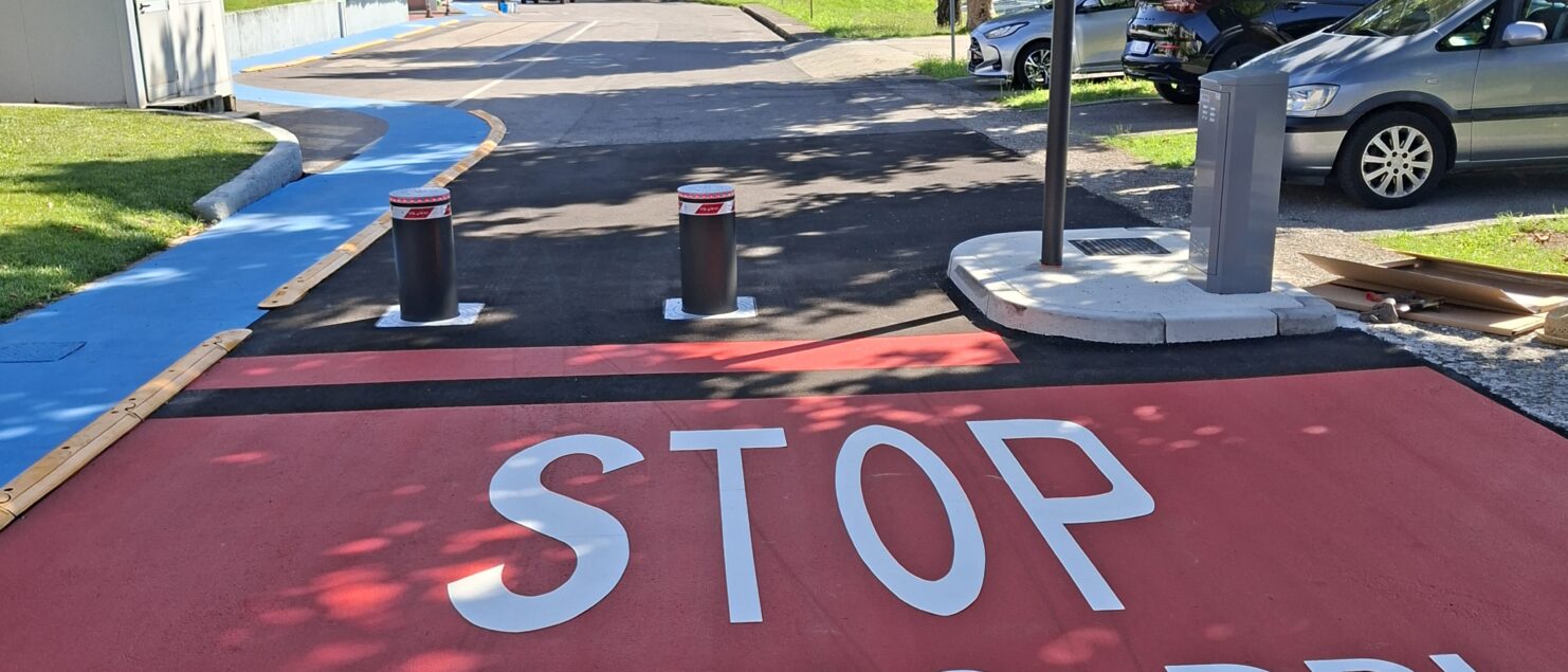 percorso pedonale di Brianzacque di Monza, sull'asfalto resinato si legge "Stop obbligo dpi" in bianco su sfondo rosso.