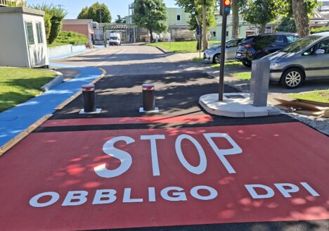 percorso pedonale di Brianzacque di Monza, sull'asfalto resinato si legge "Stop obbligo dpi" in bianco su sfondo rosso.
